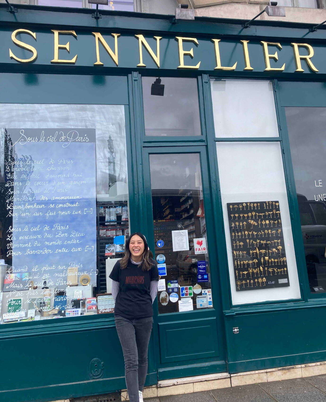 Photograph of illustrator, Sarah Doan, standing in front of art supply store smiling